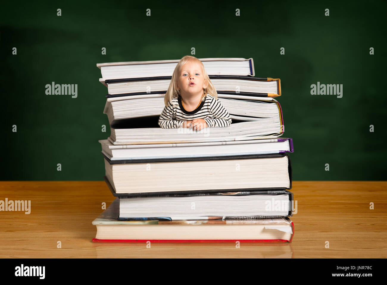 Fille blonde portant haut dénudé, popping hors de la pile de livres dans la salle de classe Banque D'Images