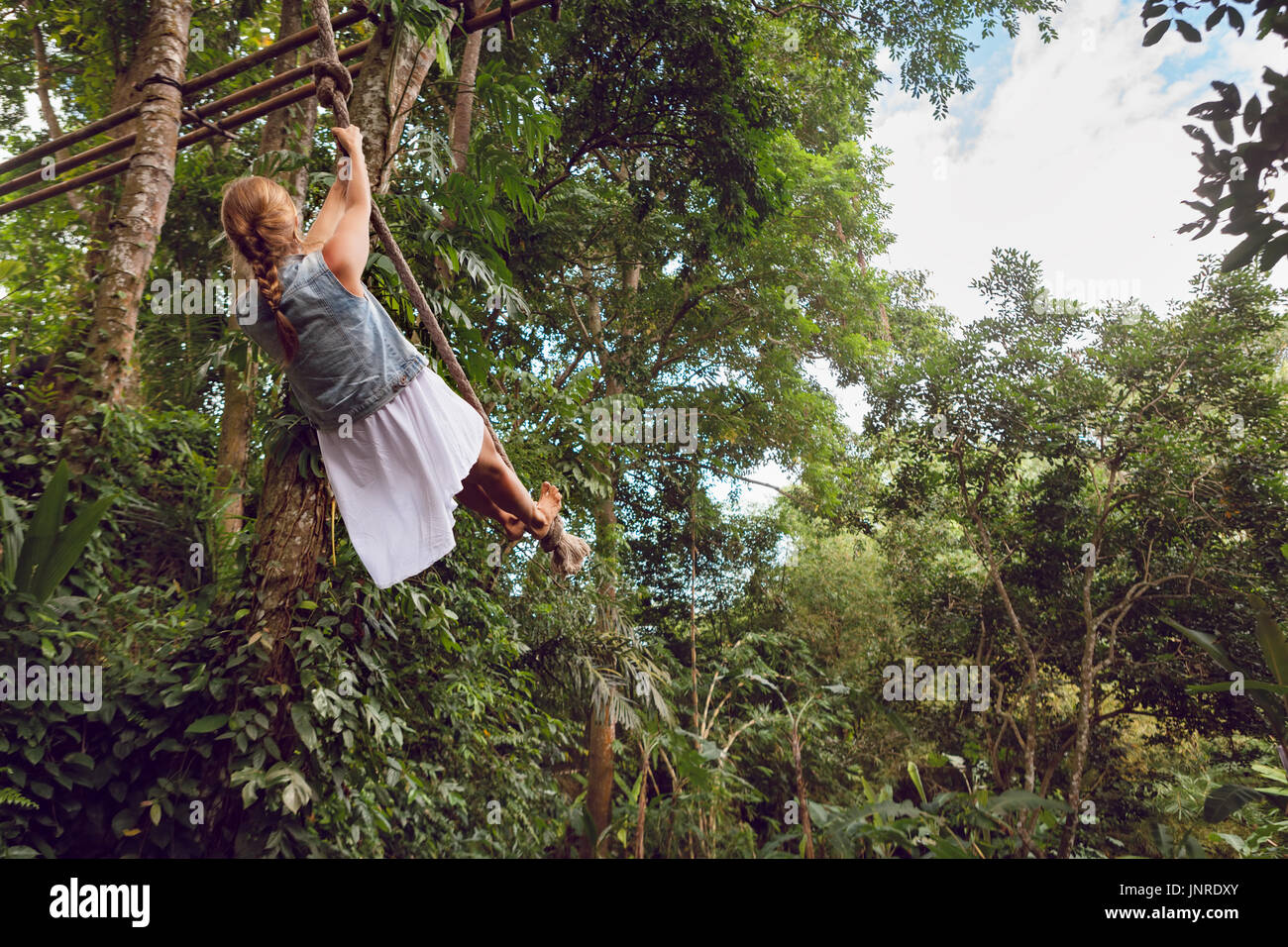 Des voyages en famille de vie. Happy young woman flying high avec plaisir sur rope swing sur fond de jungle sauvage. Aventure drôle de marcher dans la forêt tropicale. Banque D'Images