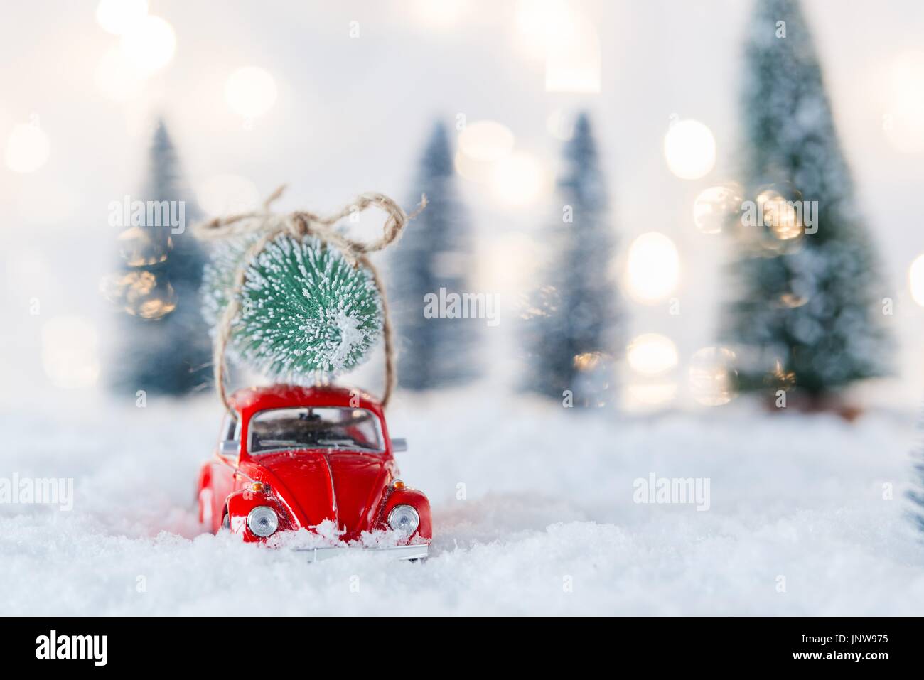 Petite voiture rouge toy Christmas Tree in snow couvertes de forêts miniatures Banque D'Images