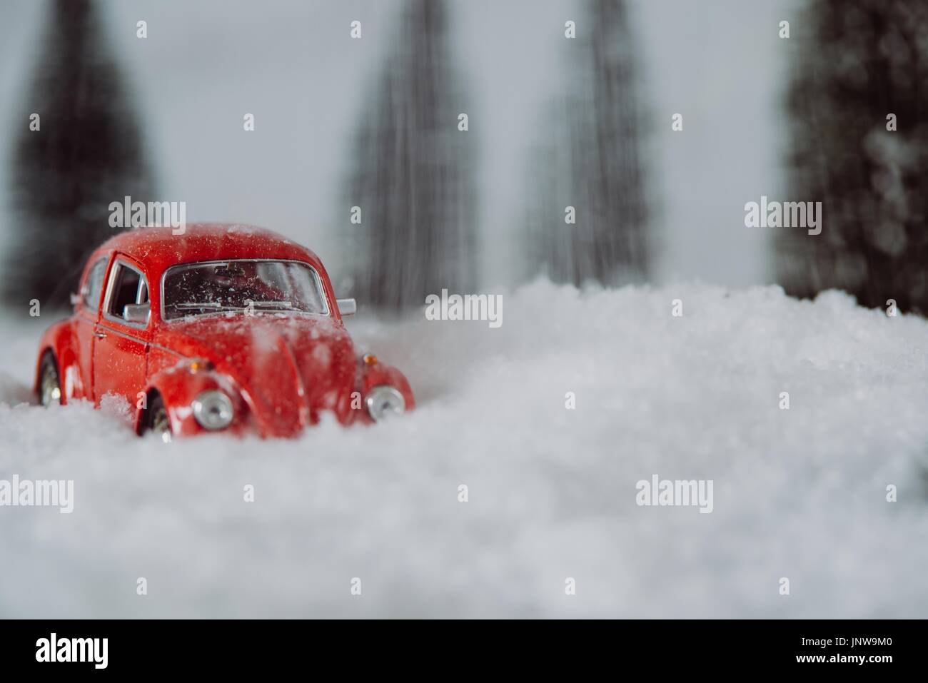 Petite voiture rouge toy coincé dans la neige en forêt miniature Banque D'Images