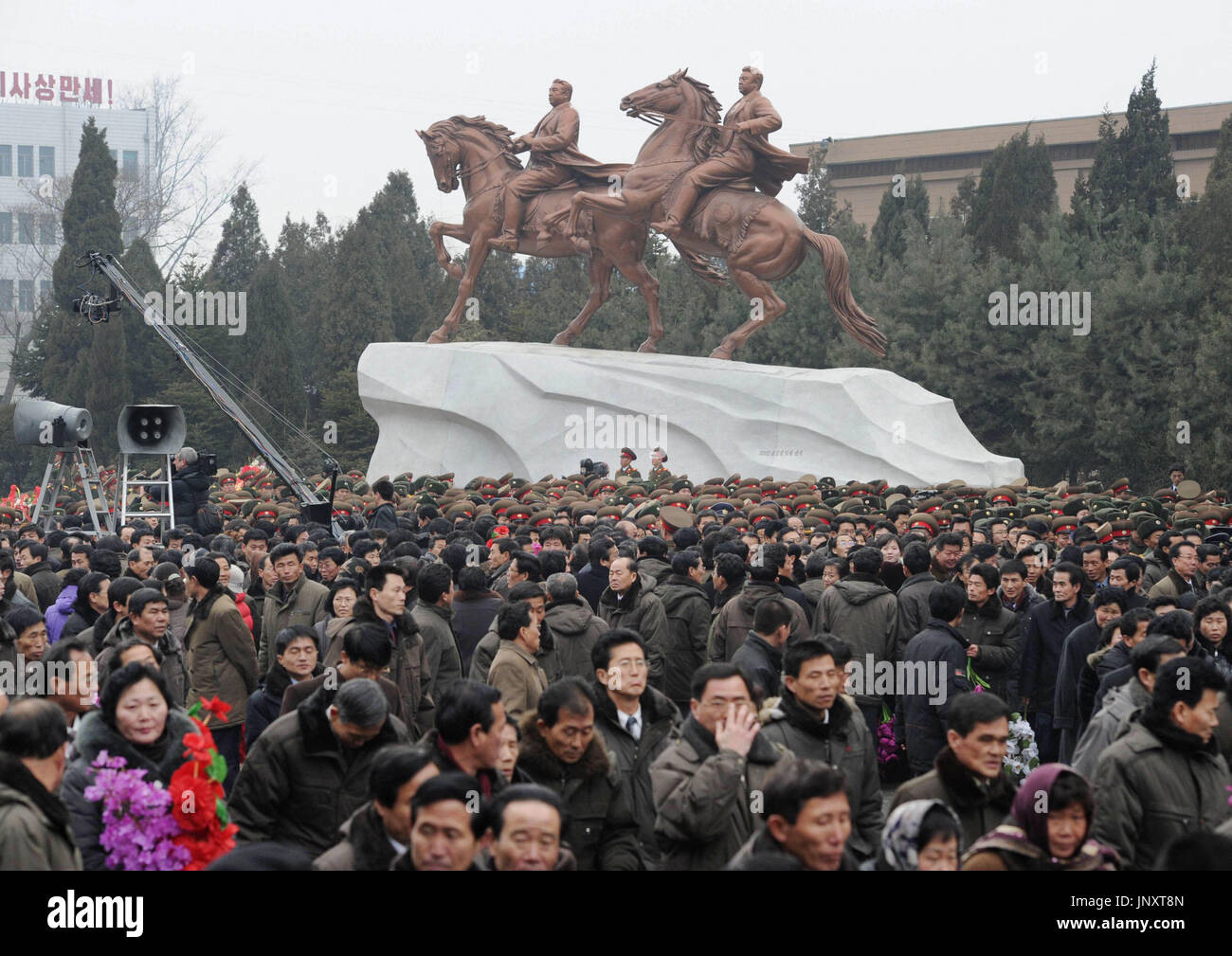 PYONGYANG, Corée du Nord - Les gens se rassemblent autour d'une statue en bronze du défunt dirigeant Kim Jong Il (R), sa première statue, et une autre statue en bronze de Kim et son père Kim Il Sung, fondateur de l'état, à cheval côte à côte, à la base de la troupe artistique Mansudae Art Studio à Pyongyang le 14 février 2012. Les statues ont été dévoilés le jour même. (Kyodo) Banque D'Images