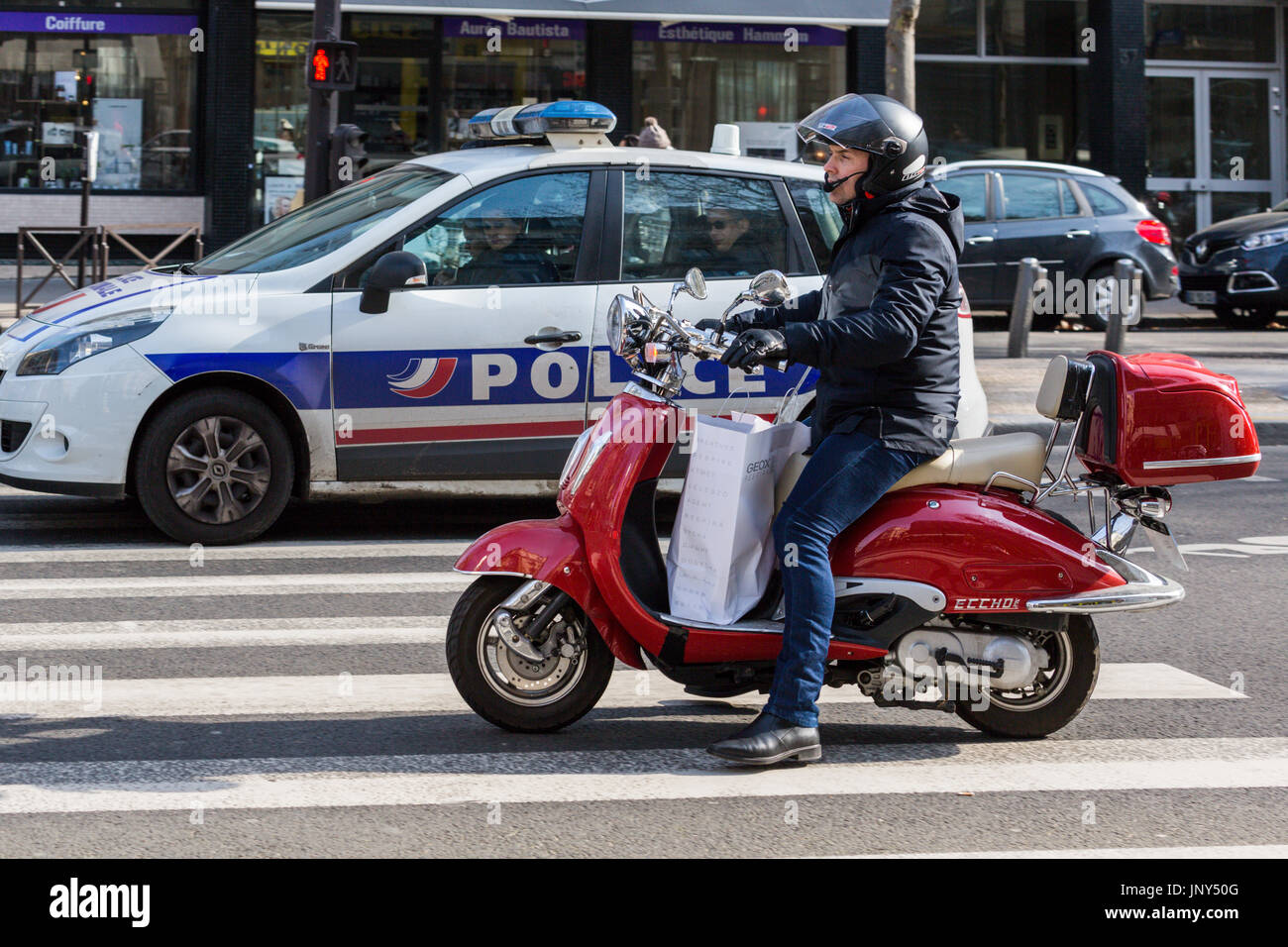 Paris. France - 27 Février 2016 : Man on motor scooter à côté d'une voiture de police sur un passage piéton sur l'Avenue Bosquet dans le 7ème arrondissement, Paris. Banque D'Images