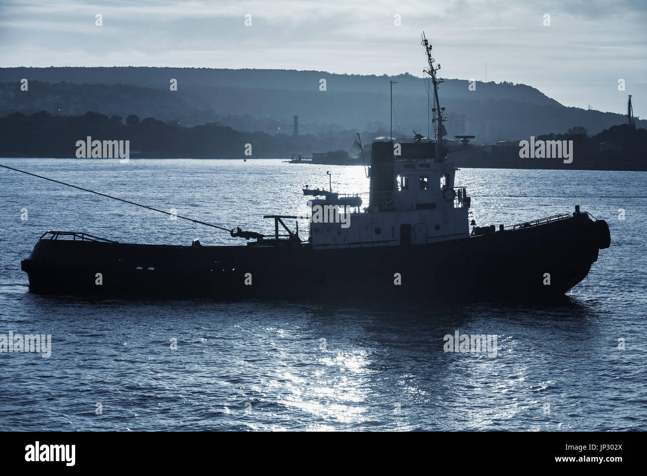 Tug boat est en cours. Le port de la mer Noire, Varna, Bulgarie. Photo silhouette sombre dans les tons bleus Banque D'Images