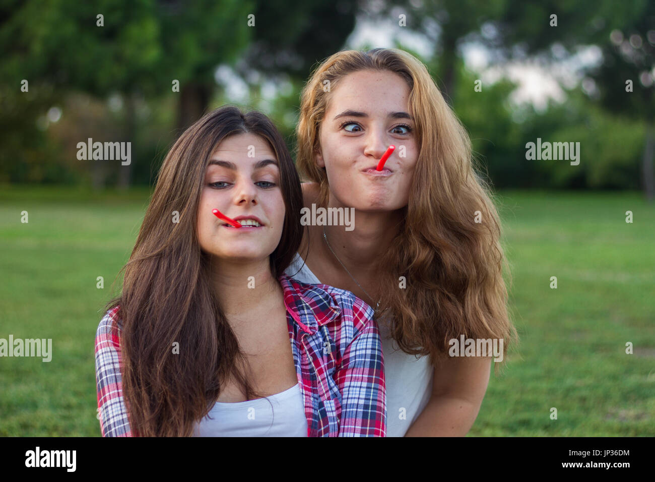 Female friends enjoying en mangeant une réglisse rouge maison de vacances dans le parc. Ils sont jeunes, l'un a les yeux bleus et l'autre est blonde. Banque D'Images