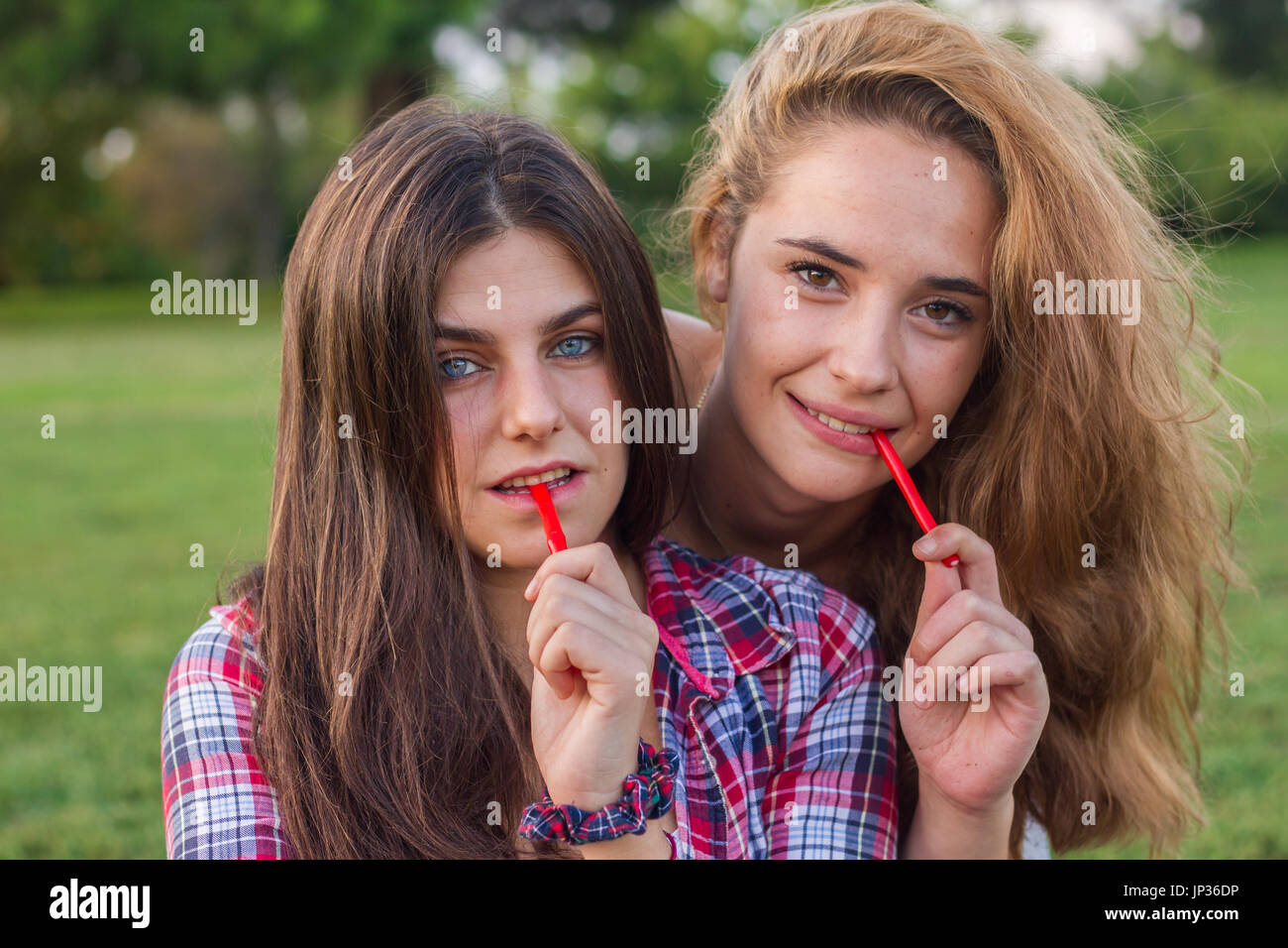 Female friends enjoying en mangeant une réglisse rouge maison de vacances dans le parc. Ils sont jeunes, l'un a les yeux bleus et l'autre est blonde. Banque D'Images