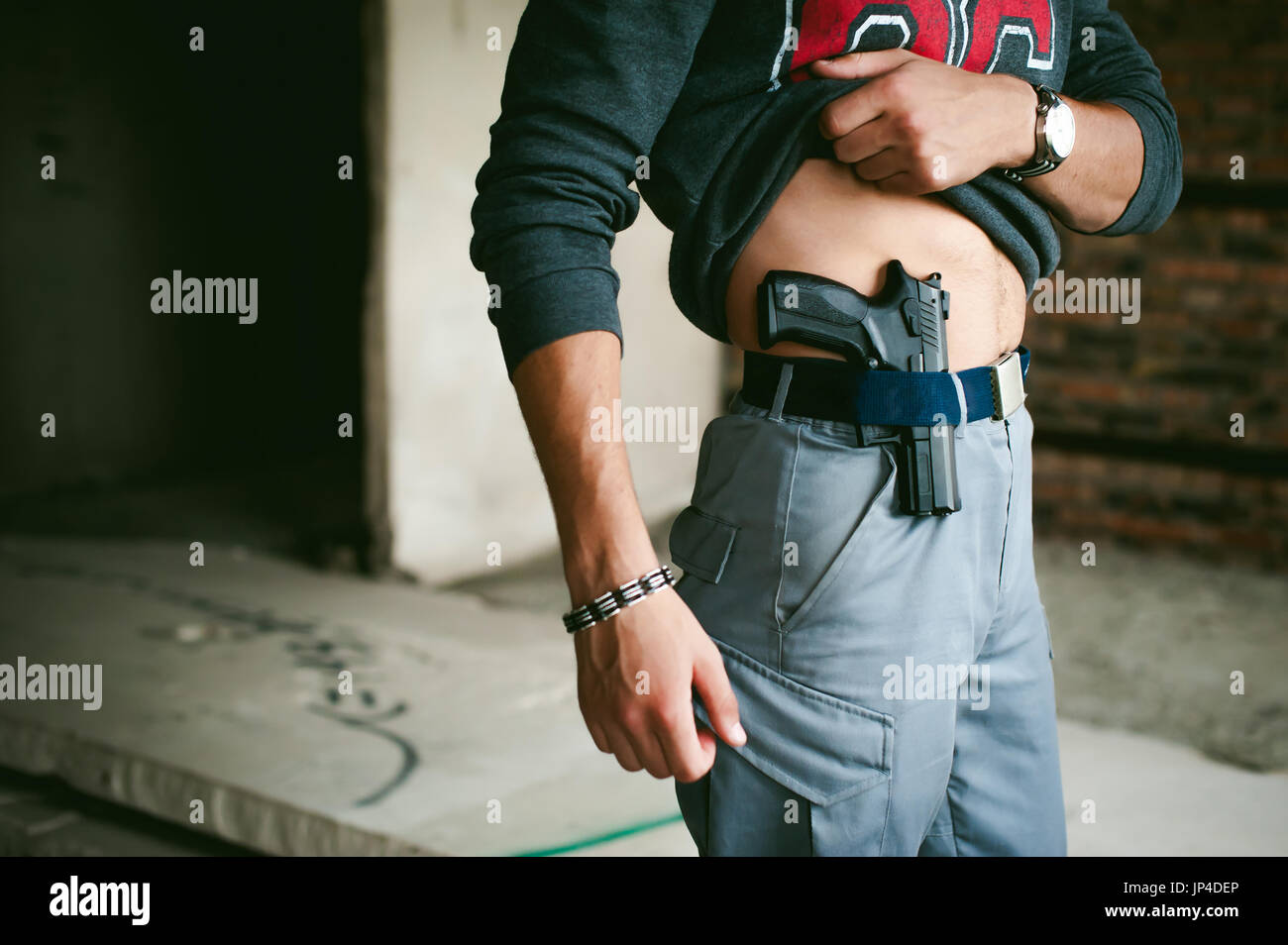 Jeune homme athlétique tenant un pistolet derrière sa ceinture Photo Stock  - Alamy