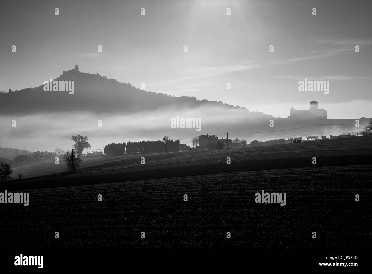 Vue d'une silhouette de l'église Saint-François d'assise au milieu de la brume, avec des champs cultivés dans l'avant-plan Banque D'Images