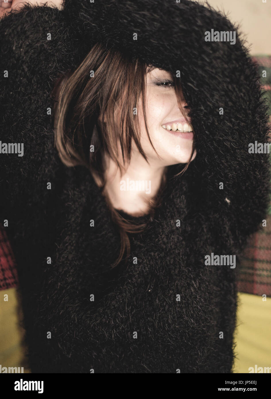 Portrait of smiling young woman wearing fluffy cavalier noir, bras levés sur la tête. Banque D'Images