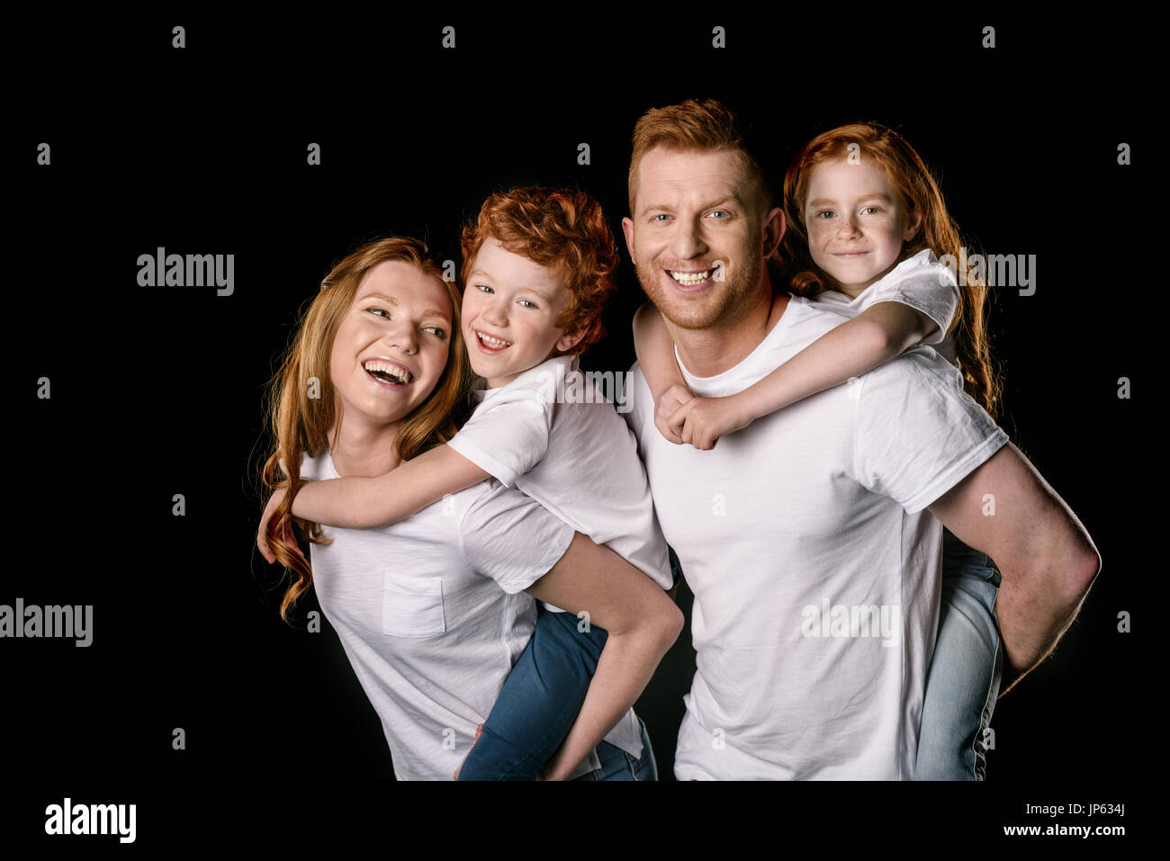 Heureux dans la famille roux blanc T-shirts smiling isolated on black Banque D'Images