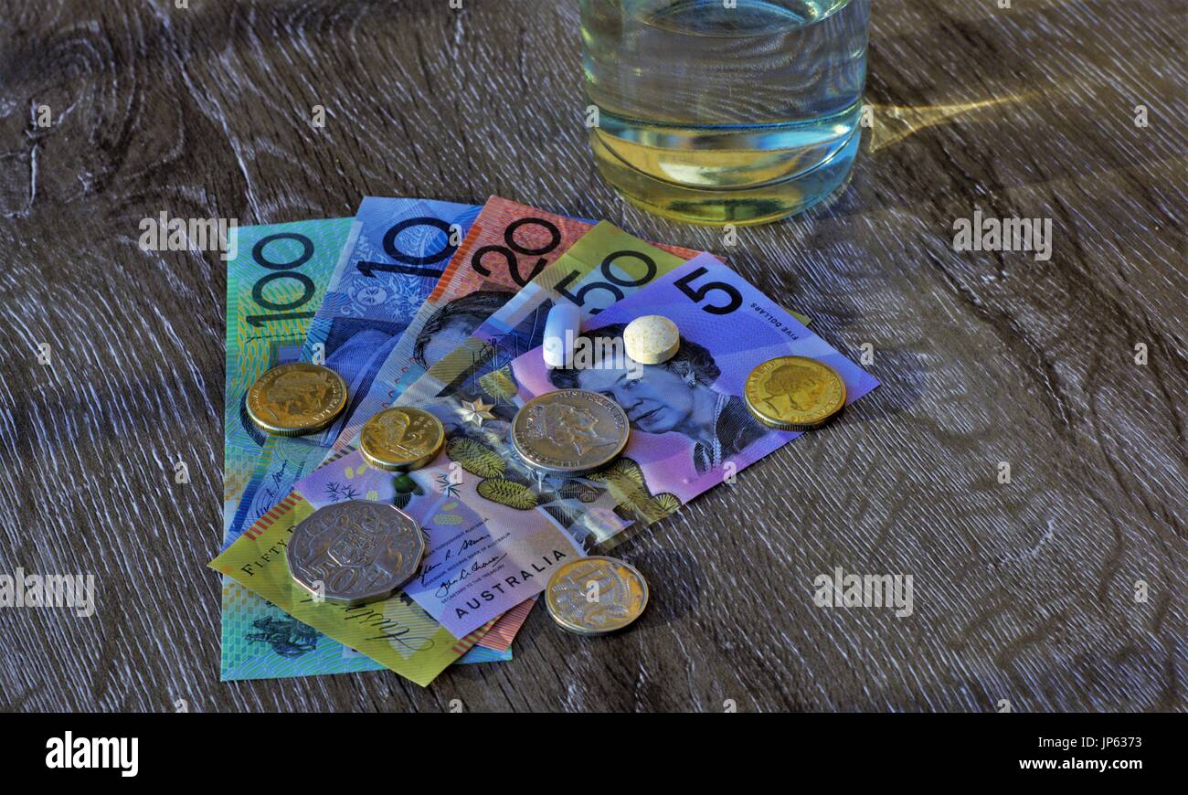 Médicament comprimés sur dollars australiens, verre d'eau. Banque D'Images