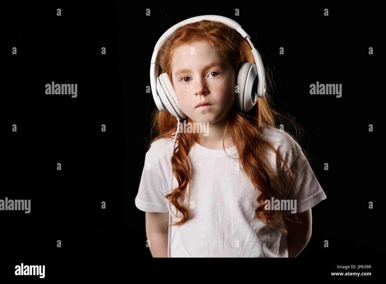 Portrait de petite fille en listenign music headphones isolated on black Banque D'Images