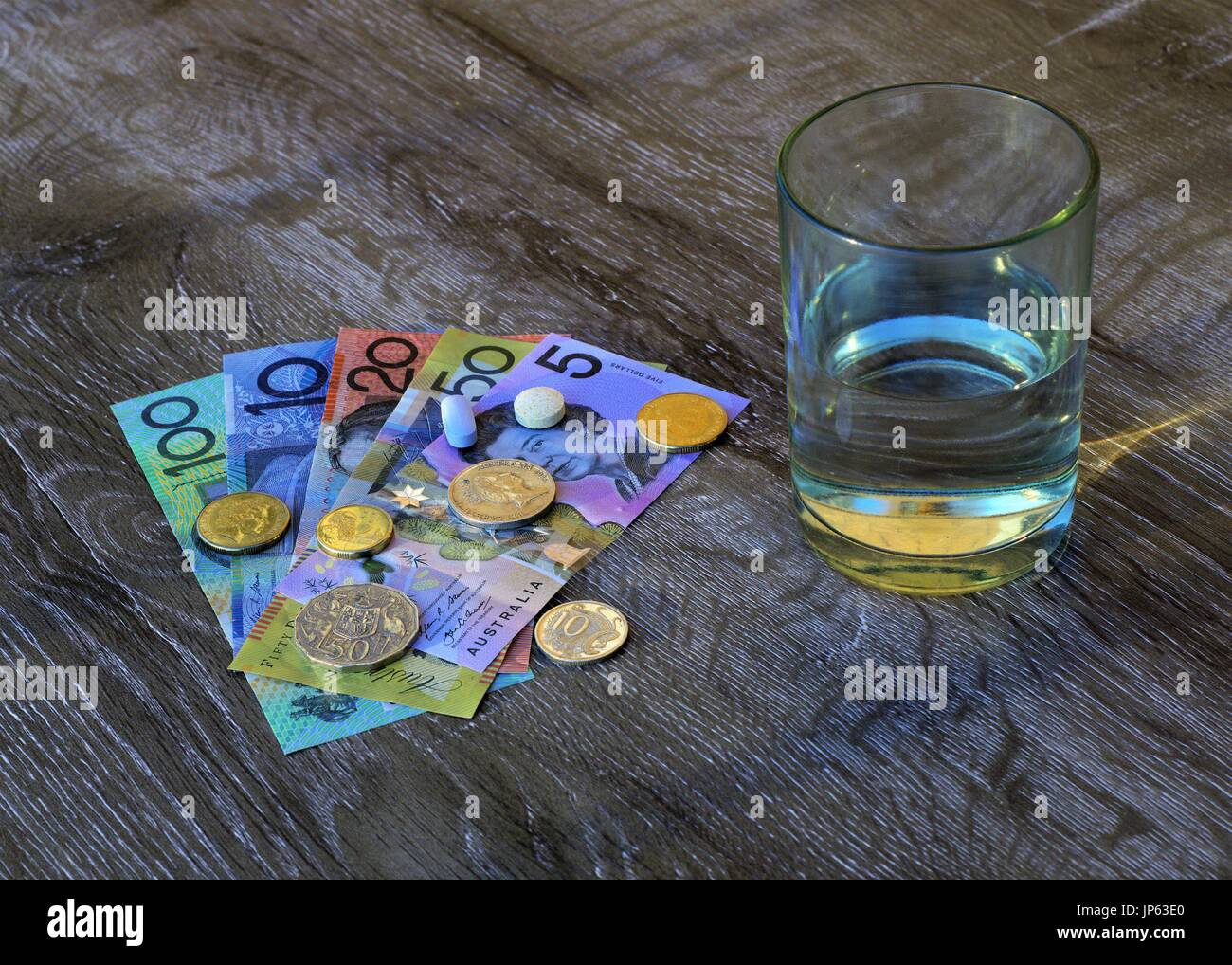 Médicament comprimés sur dollars australiens, verre d'eau. Banque D'Images