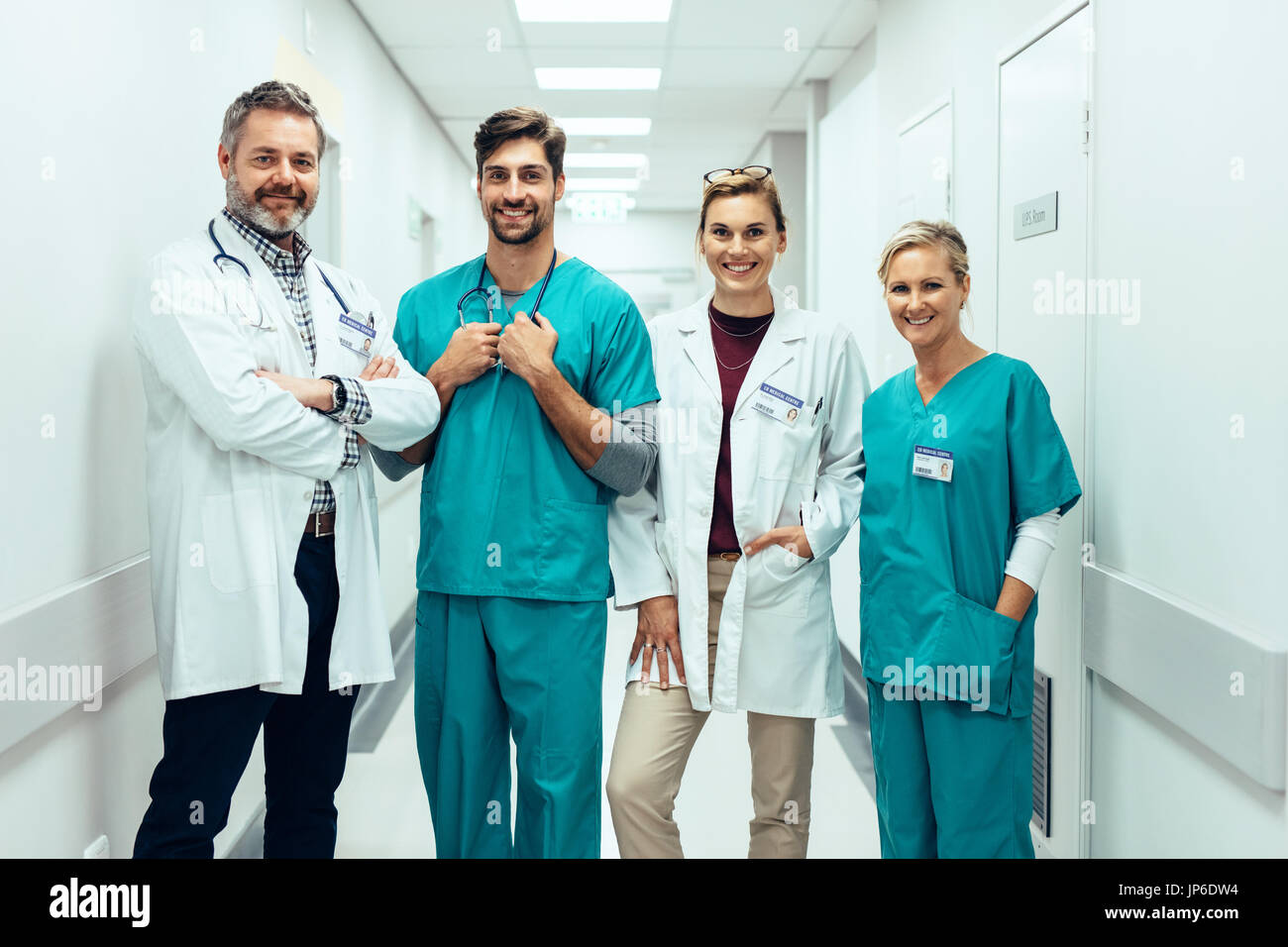 Portrait de professionnels médicaux positifs debout dans le couloir et en regardant la caméra. Groupe d'ambulanciers smiling in hospital corridor. Banque D'Images