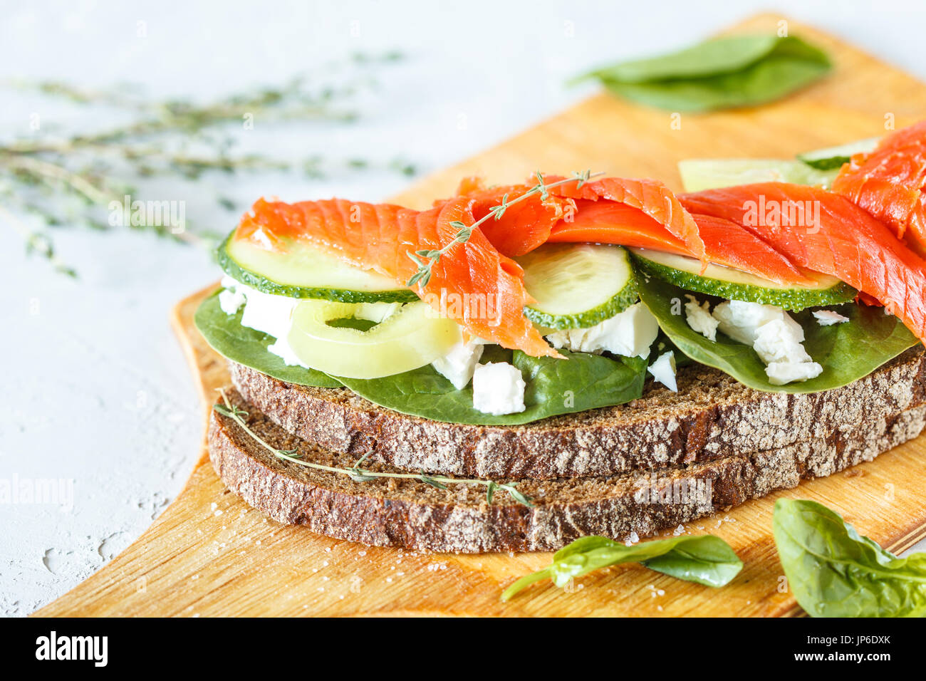 Sandwich au saumon fumé, légumes et fromage blanc sur une planche de bois. Banque D'Images