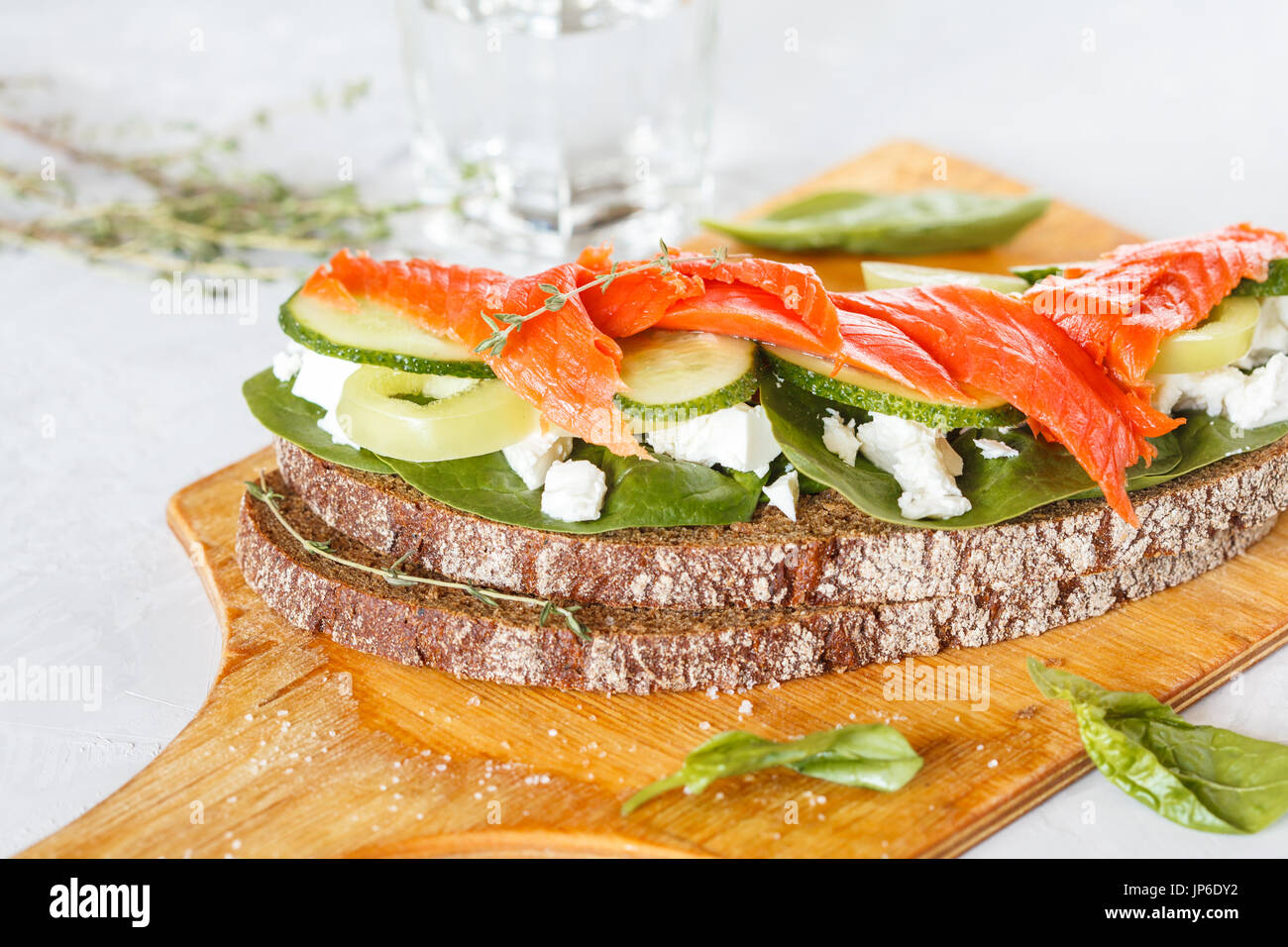 Sandwich au saumon fumé, légumes et fromage blanc sur une planche de bois. Banque D'Images