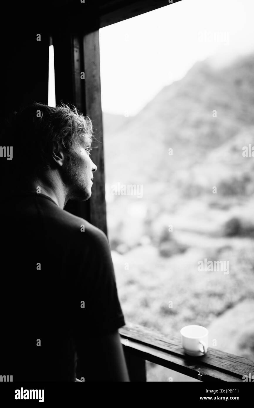 L'homme regarde par fenêtre sur les montagnes Photo Stock - Alamy
