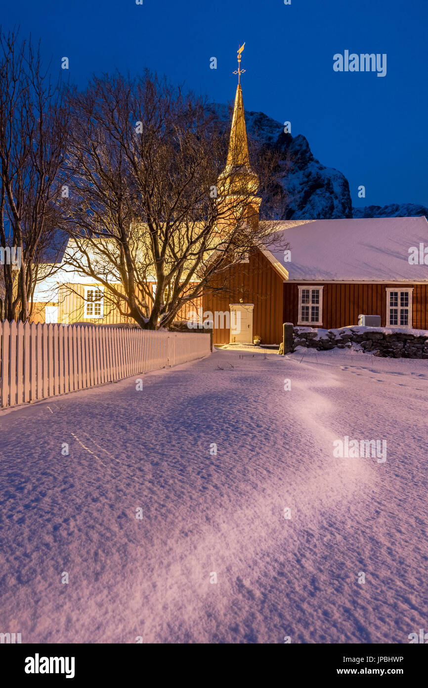 Lumières sur l'église en bois typique entouré de neige Flakstad Lofoten, Norvège du Nord Europe Banque D'Images