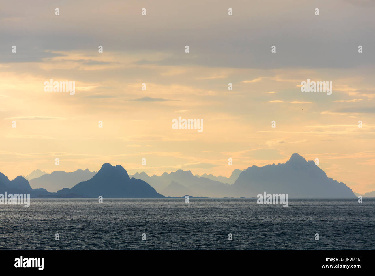 Soleil de minuit s'allume les pics rocheux surplombant la mer claire Lofoten, Norvège Europe Banque D'Images