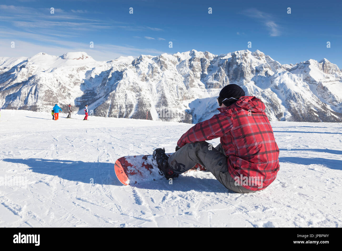 Un surfeur est assis sur la neige à la recherche vers le groupe de Brenta, province de Trento, Trentino Alto Adige, Italie, Europe Banque D'Images