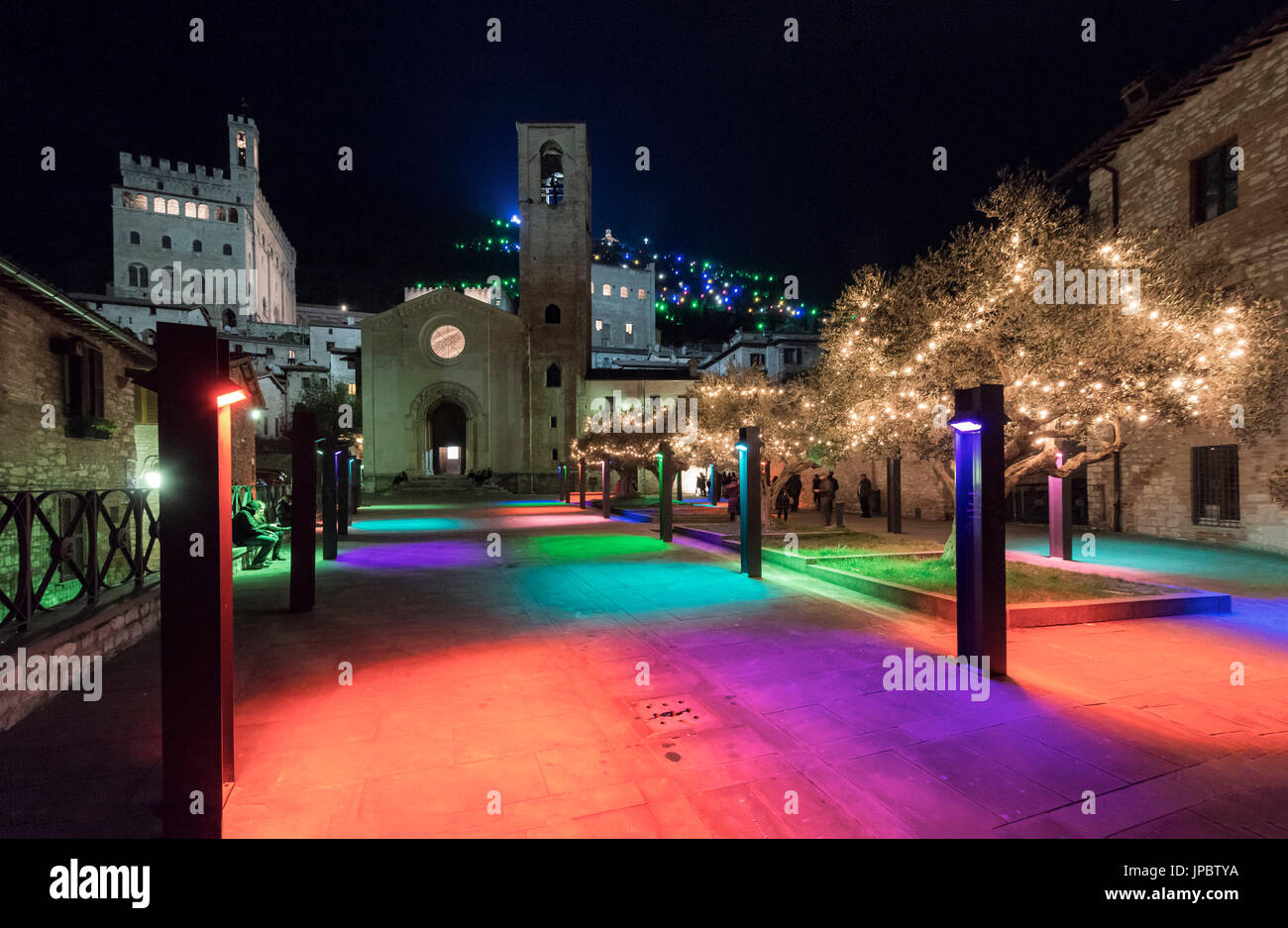 La place San Giovanni éclairée avec des lumières colorées et d'arbres de Noël par nuit, avec Consoli's Palace et église San Giovanni, Gubbio, Ombrie, Italie Banque D'Images