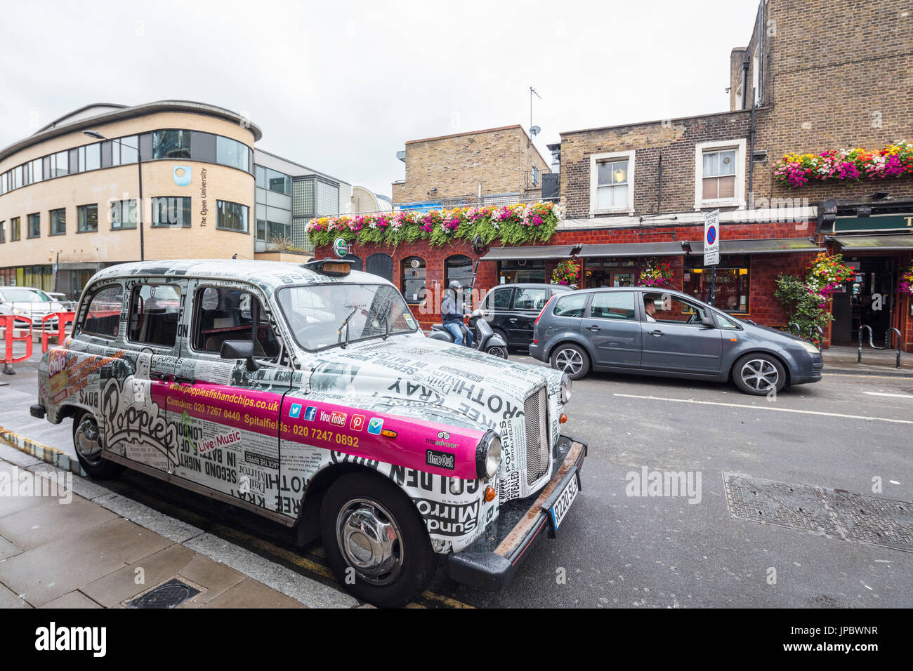 Taxi couvert d'autocollants publicitaires dans les rues commerçantes de Camden Market North West London United Kingdom Banque D'Images