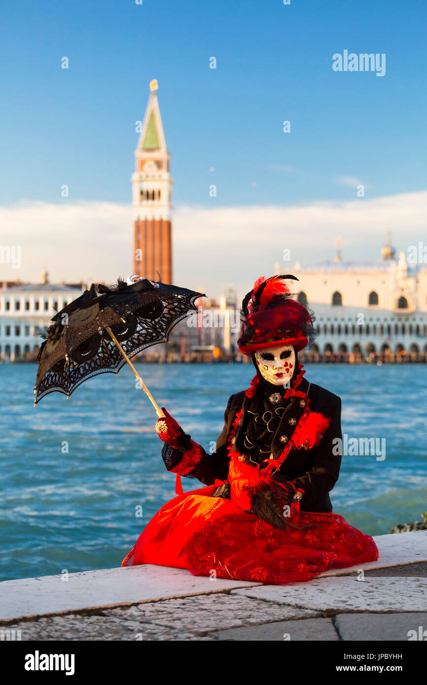 Portrait de femme au costume rouge et masque typique du Carnaval de Venise avec la Place St Marc dans l'arrière-plan Vénétie Italie Europe Banque D'Images