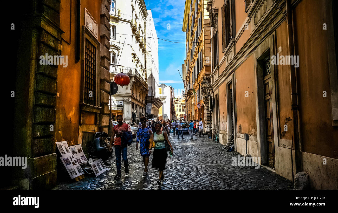 Une jeune femme et deux jeunes hommes marchant dans une allée ombragée dans le centre historique de Rome sur l'Italie centery un après-midi d'été Banque D'Images