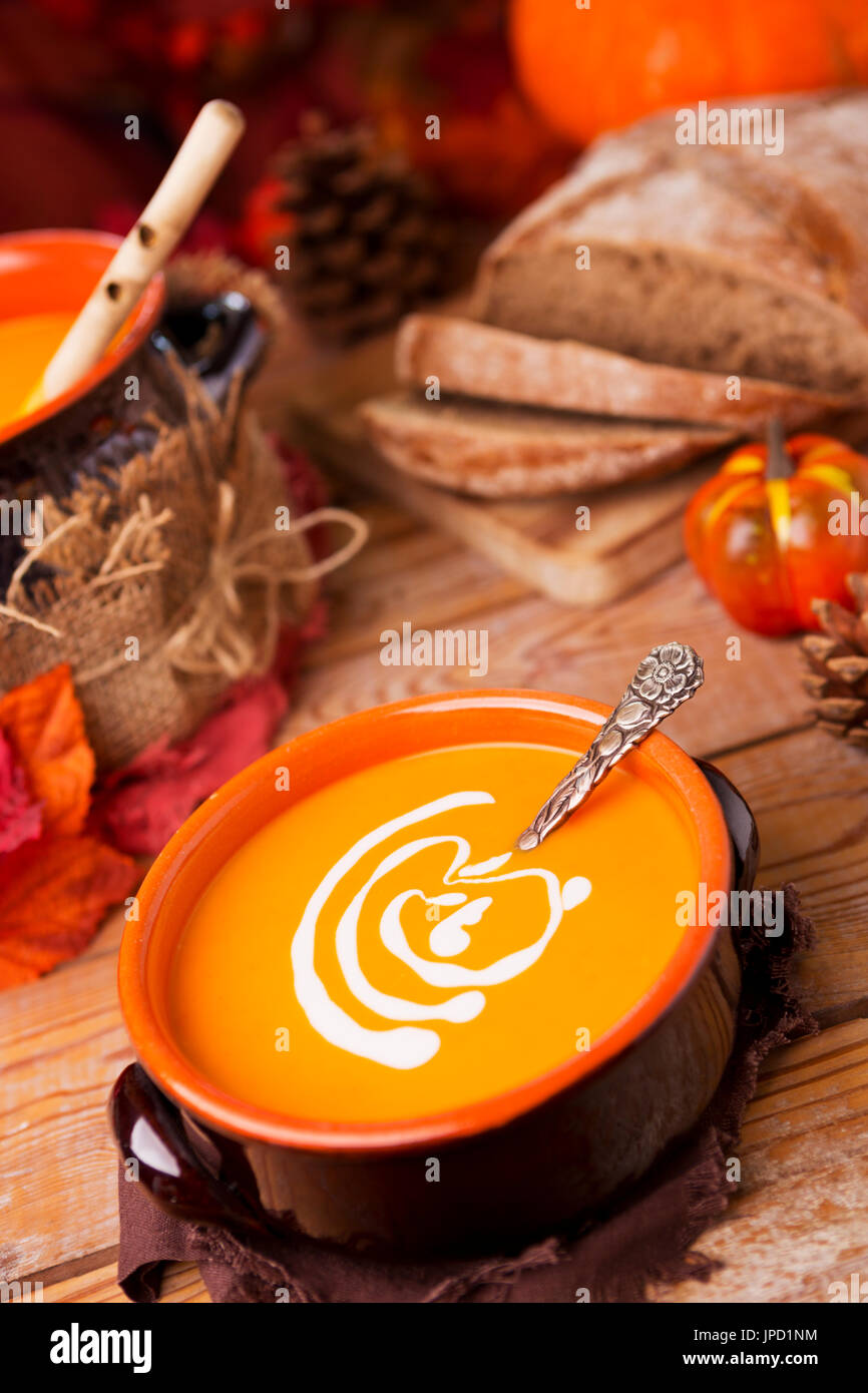 Un bol de soupe au potiron crémeuse faite maison sur une table rustique avec des décorations d'automne. Banque D'Images