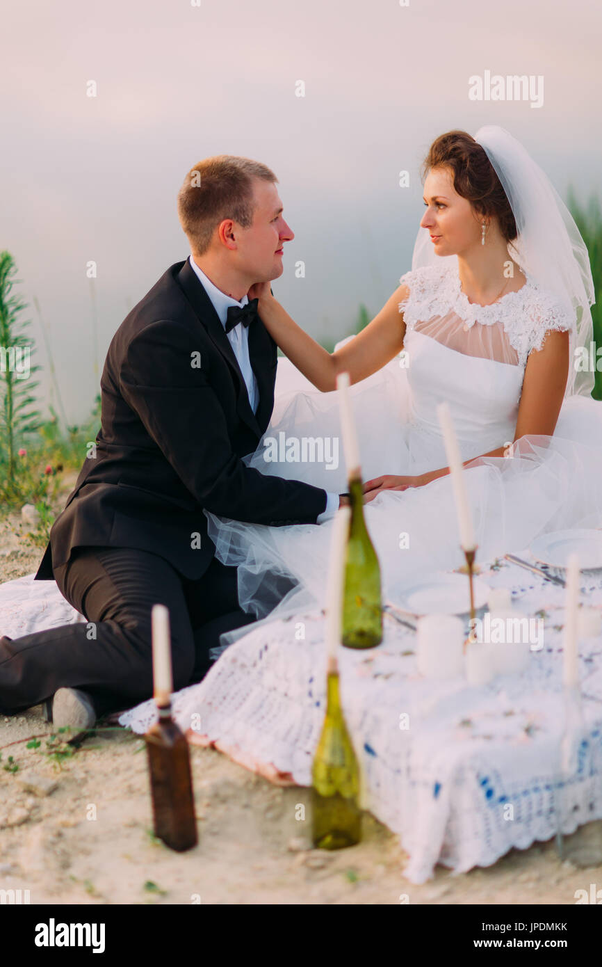 L'épouse, c'est flatter le visage de l'époux au cours de leur pique-nique sur la côte. Banque D'Images