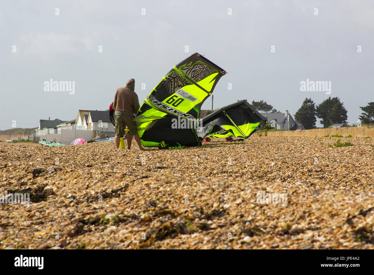 Un couple de jeunes hommes lutte contre une forte brise de préparer leurs para glider pour une après-midi sportive à la plage dans la région de Hampshire, Titchfield th Banque D'Images