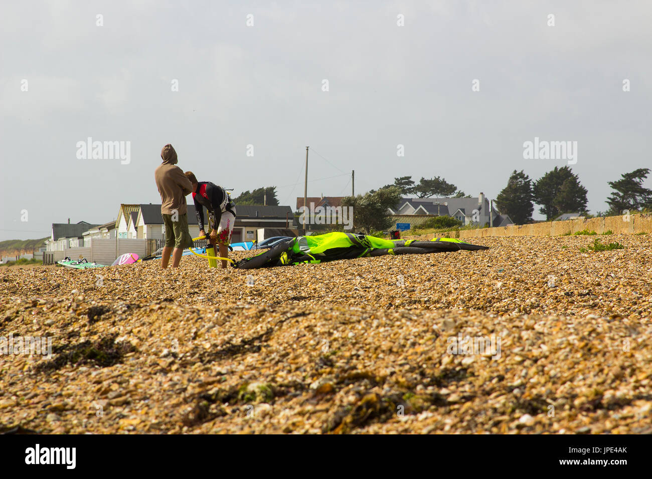 Un couple de jeunes hommes lutte contre une forte brise de préparer leurs para glider pour une après-midi sportive à la plage dans la région de Hampshire, Titchfield th Banque D'Images