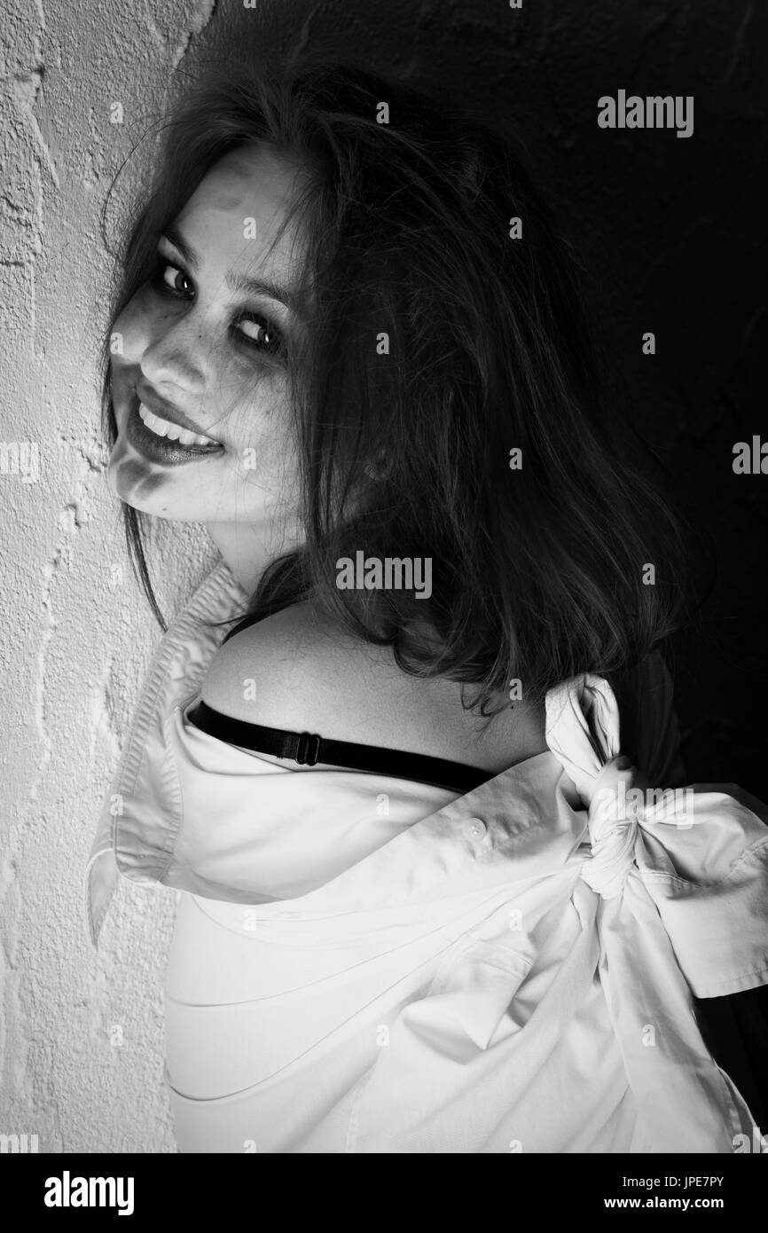 Crazy girl assez amusant avec des cheveux et enduit mur près de cosmétiques looking at camera, rire, monochrome Banque D'Images