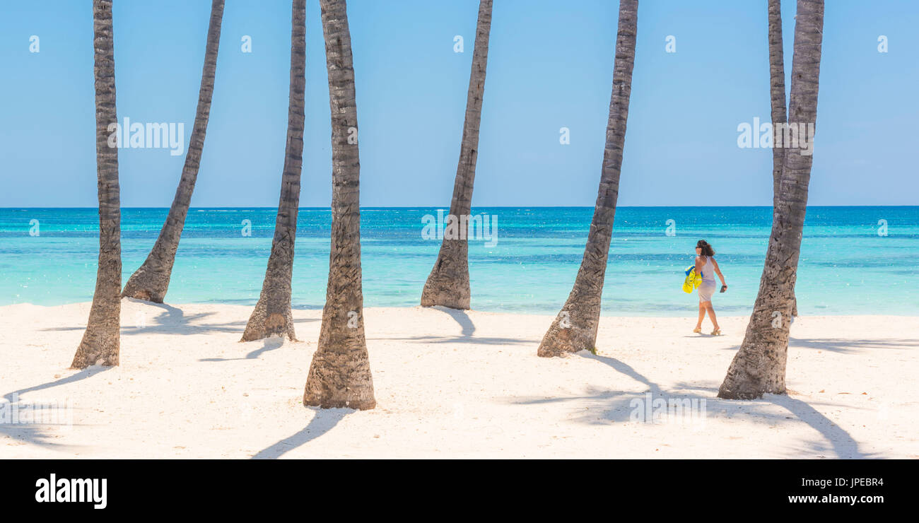 Juanillo Beach (playa Juanillo), Punta Cana, République dominicaine. Femme marche sur la plage bordée de palmiers (MR). Banque D'Images