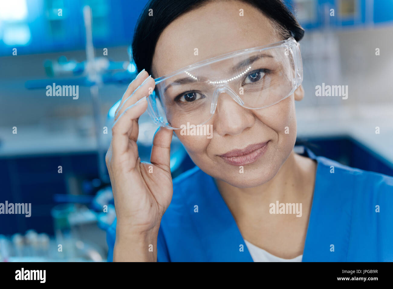 Cheerful attractive woman holding ses lunettes de protection Banque D'Images