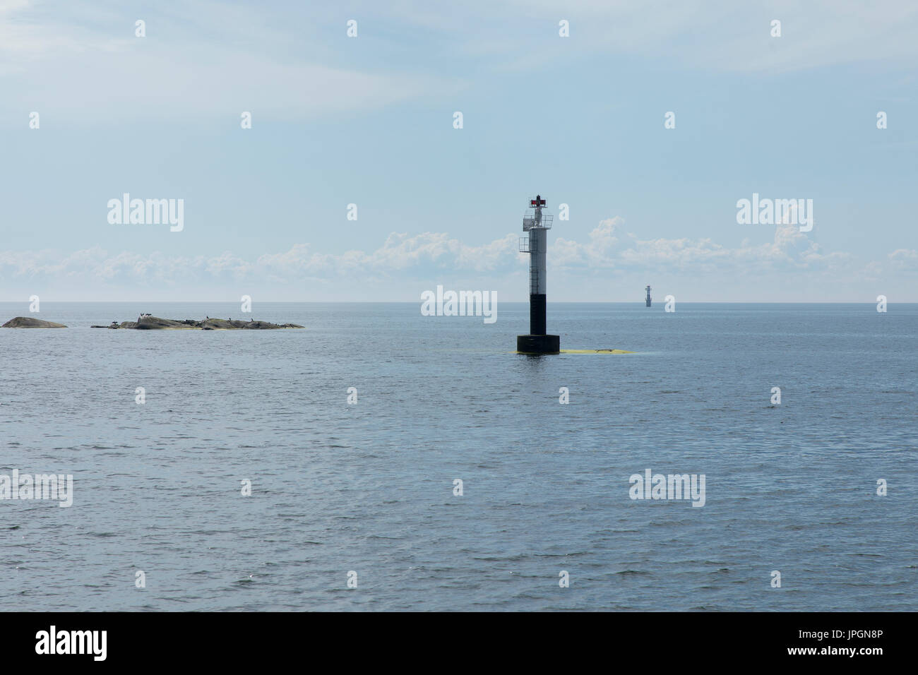 Face à la mer avec un petit phare et une petite île avec quelques brirds Banque D'Images