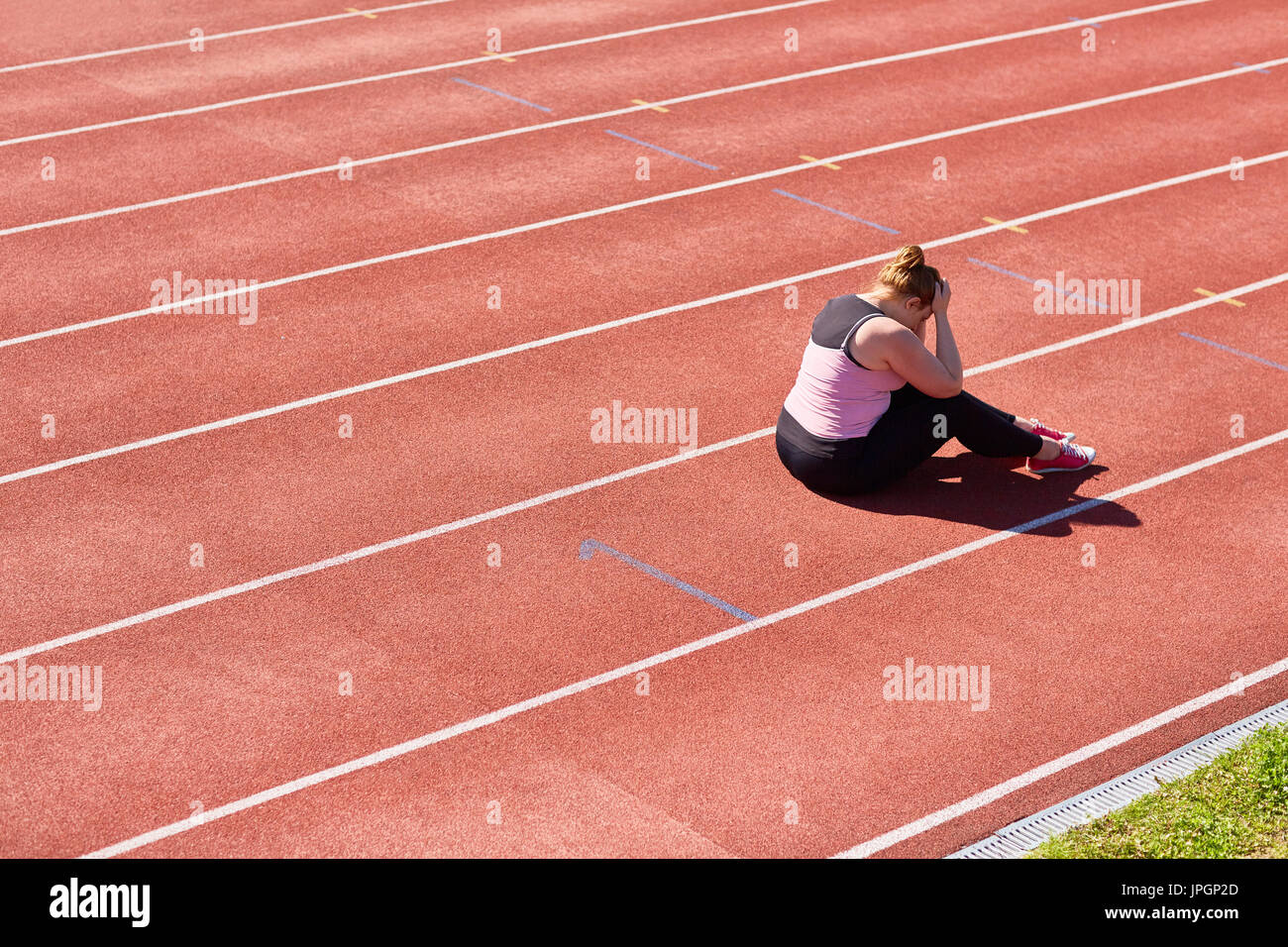 Frustrés chubby woman sitting on stadium racetrack avec sa tête dans les mains Banque D'Images