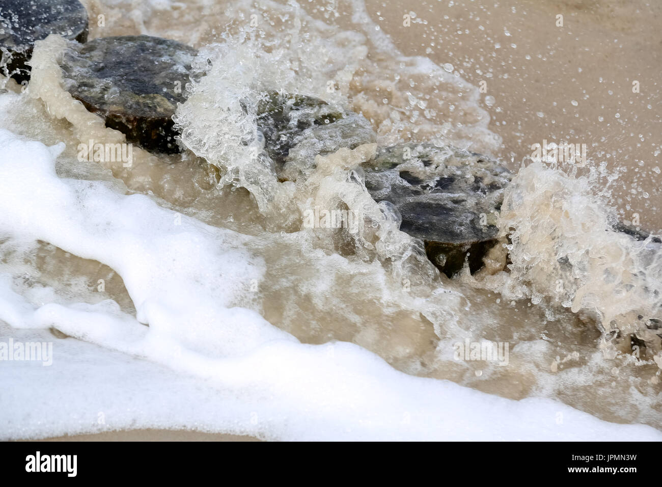 La mer vague éclabousse le brise-lames en bois. C'est vue sur la plage de sable de Kolobrzeg en Pologne Banque D'Images