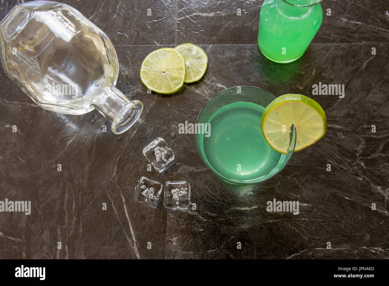 Télévision laïcs de vintage cocktail gimlet gin garni de tranches de citron vert, bouteille de gin, le jus de lime avec des cubes de glace sur le noir . Banque D'Images