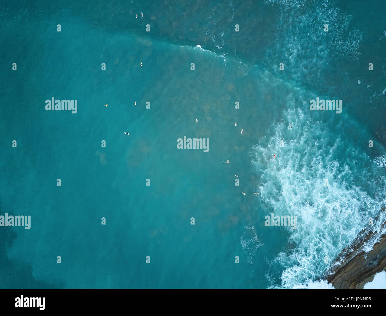 Groupe de surfeurs en attente de vague dans l'océan bleu vue aérienne drone Banque D'Images