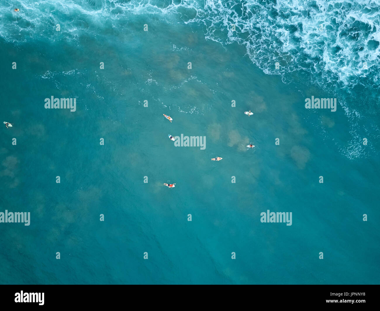Les surfeurs nager dans l'eau bleue aerial vue ci-dessus. Vue de dessus sur surfer dans l'eau bleu de l'onde pour attendre Banque D'Images
