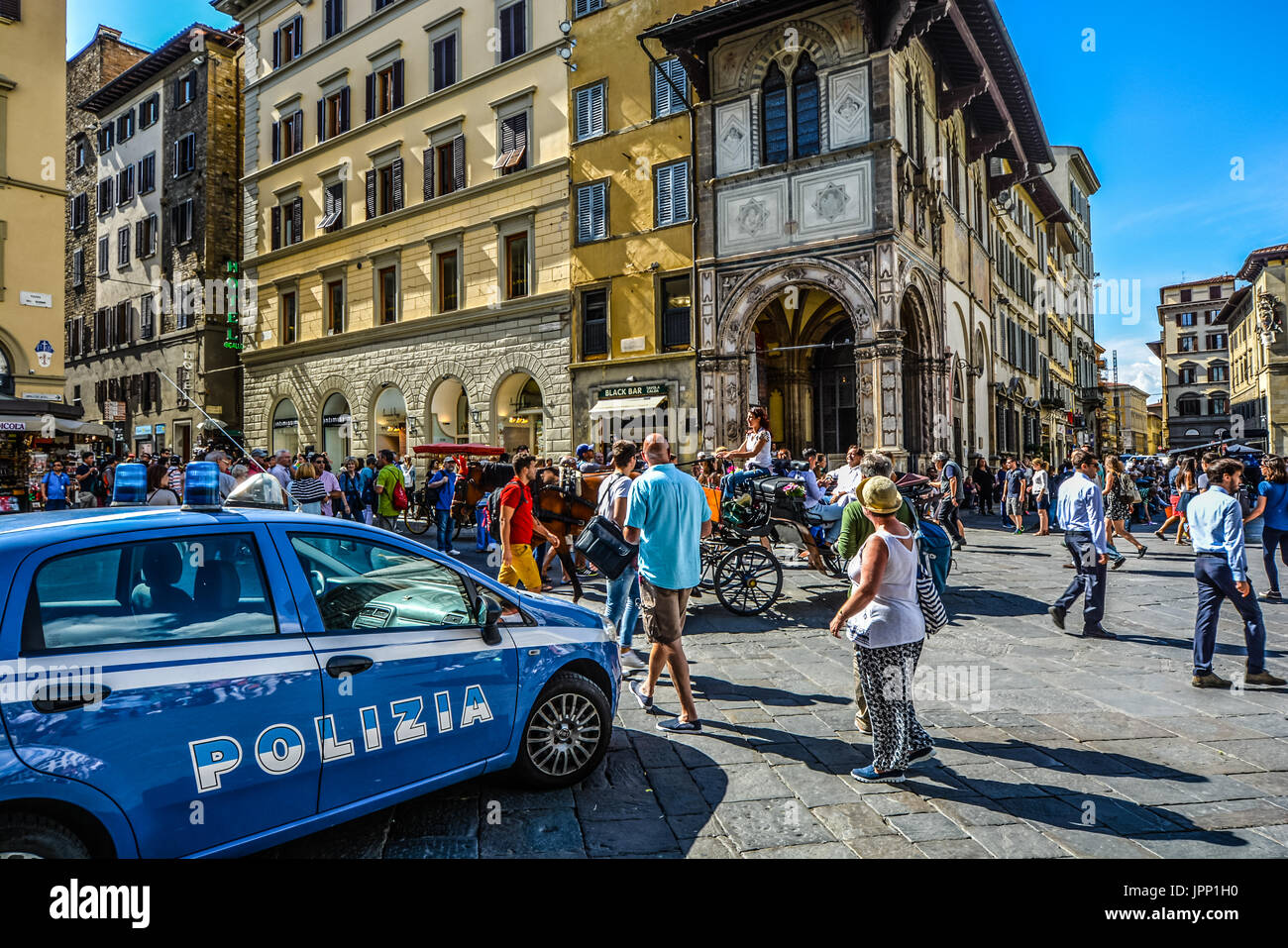 Une place près du Duomo à Florence Italie occupé par les touristes, une voiture de police et un cheval et un chariot avec une femme Italienne de la conduite sur une chaude journée d'été Banque D'Images