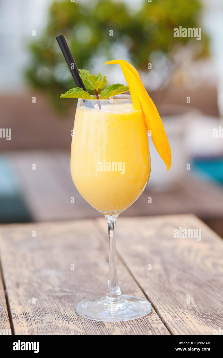 Smoothie mangue juteuse de en verre avec paille et décoration menthe sur table en bois. Jus sains. Banque D'Images