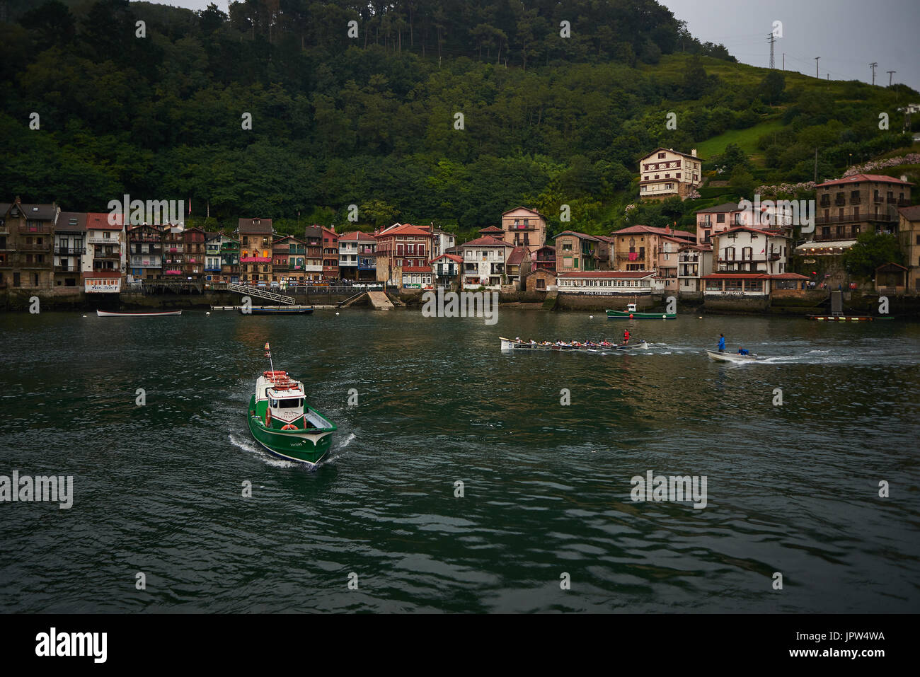 Traversée en bateau et d'un service de formation Trainera en face du village de pêcheurs de Pasajes de San Juan (Pasai Donibane), à la tombée de la nuit. Pays Basque, Espagne. Banque D'Images