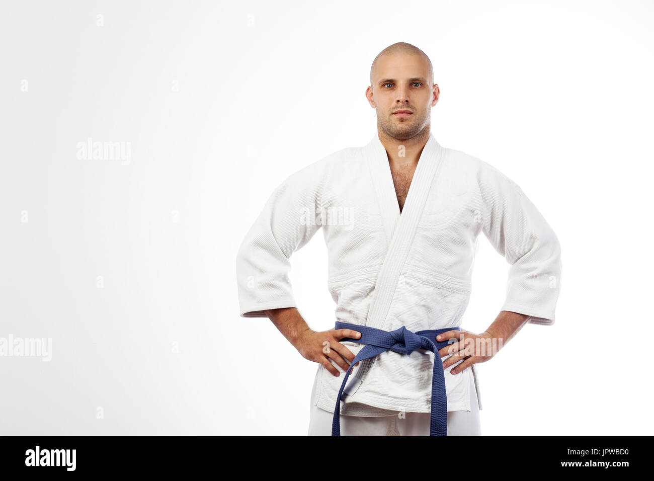 Un jeune homme fort dans un kimono blanc de sambo, jiu jitsu et d'autres  arts martiaux avec une ceinture bleu sur blanc fond isolé pose, mains  tenant o Photo Stock - Alamy