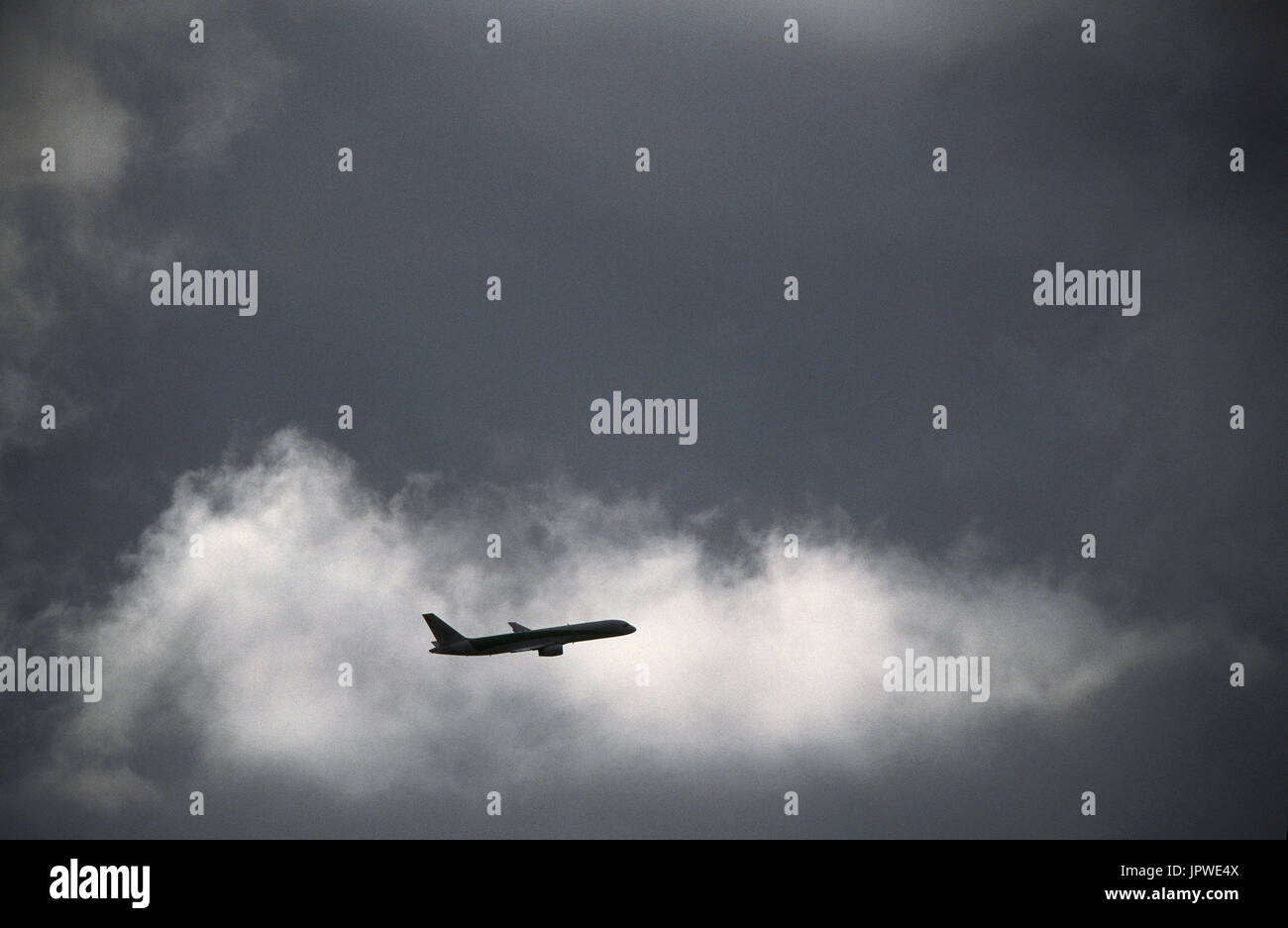 Boeing 757-200 en route escalade parmi les nuages sombres Banque D'Images