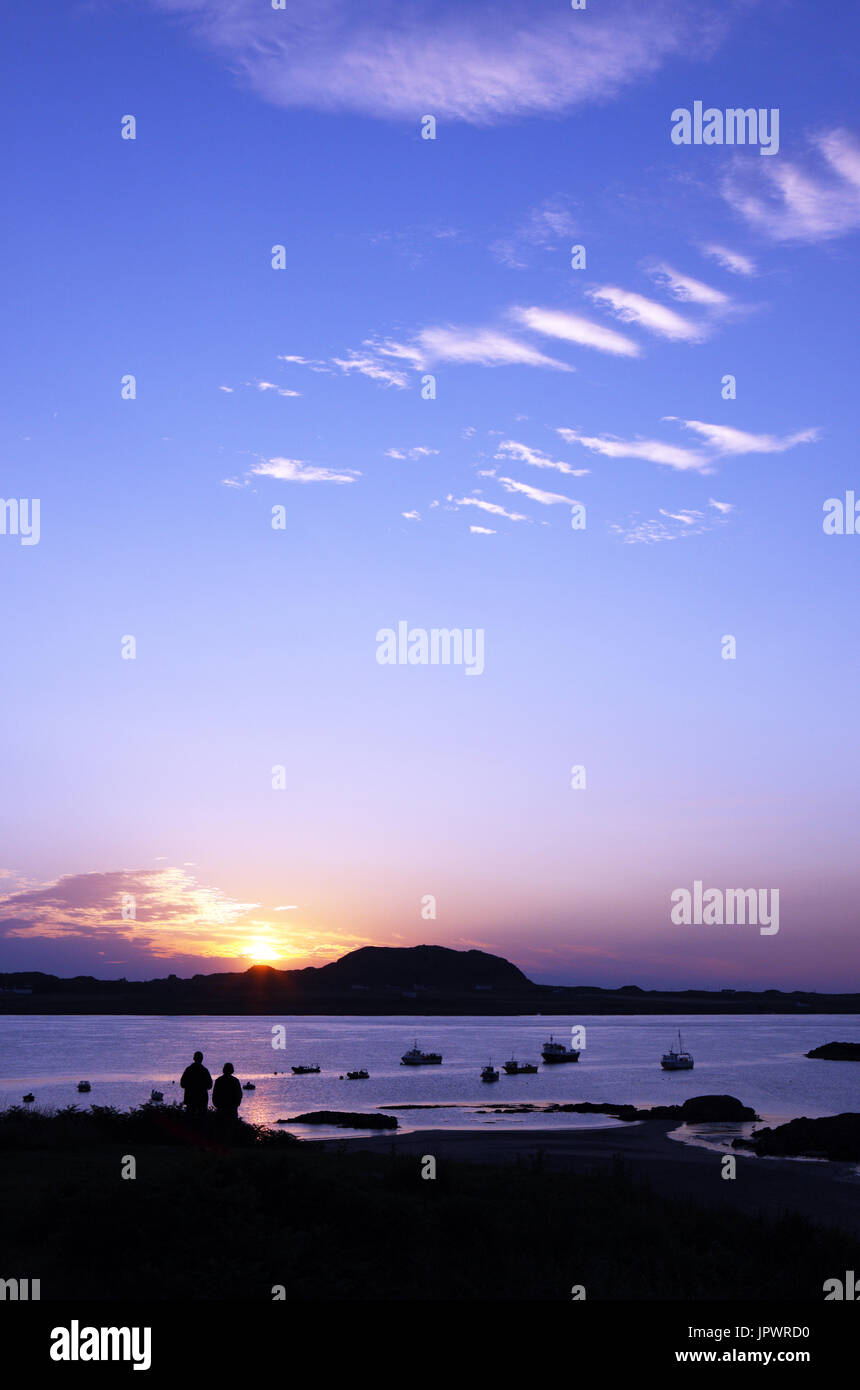 Couple regardant le coucher de soleil sur Iona de Fionnphort sur l'île de Mull, en Ecosse Banque D'Images