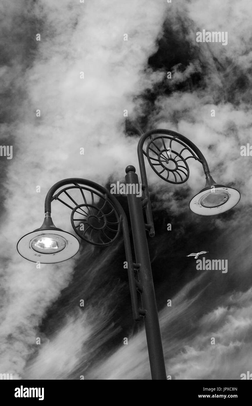 Ammonite ornée, lampadaires design un allumé et l'un n'est pas allumée, sur la promenade à Lyme Regis, dans le Dorset en noir et blanc (monochrome) - idéal pour la couverture du livre Banque D'Images