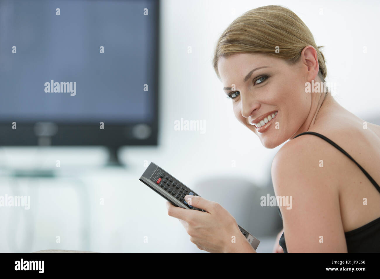 Young woman with remote devant plat Banque D'Images