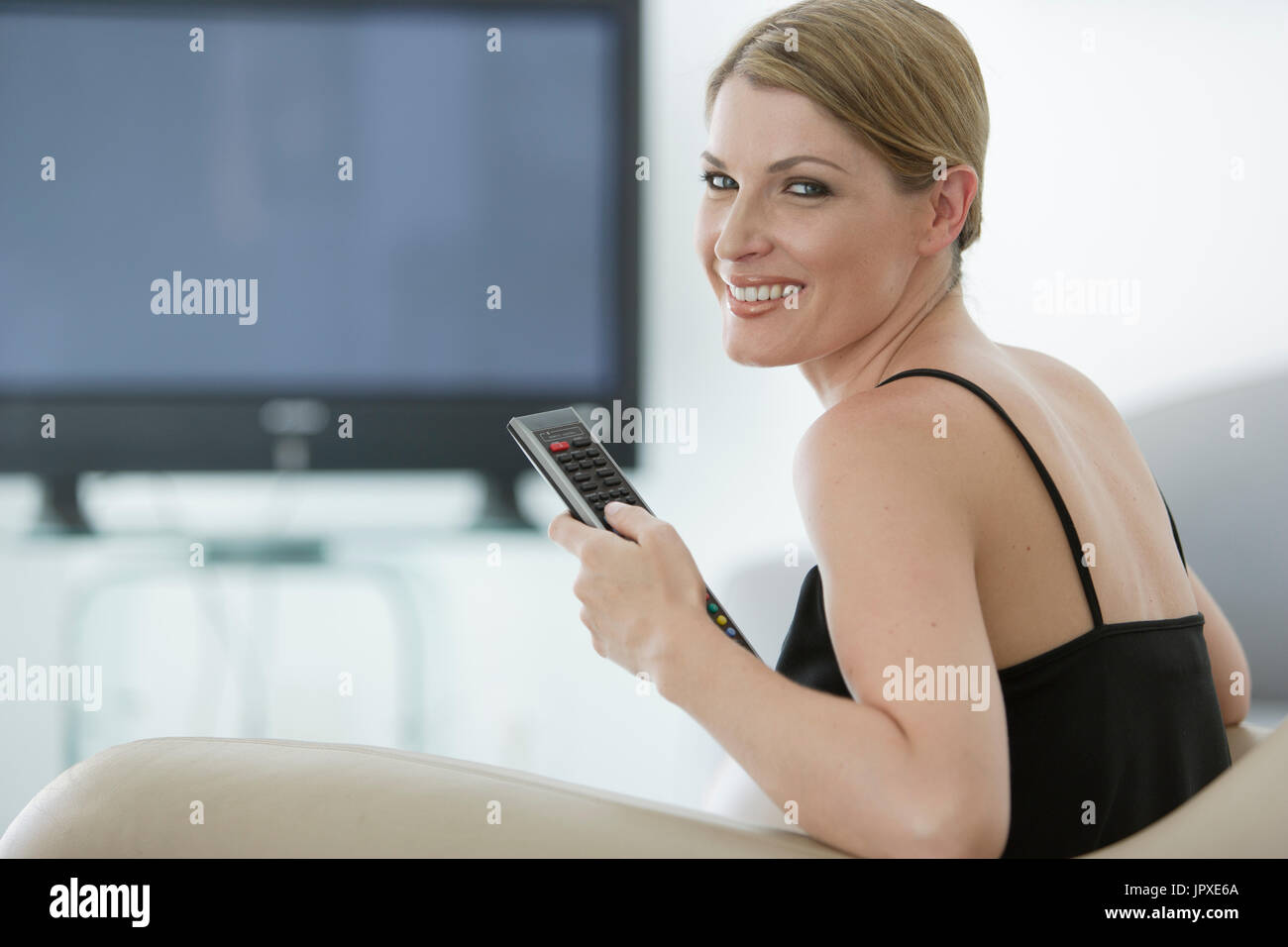 Young woman with remote devant plat Banque D'Images