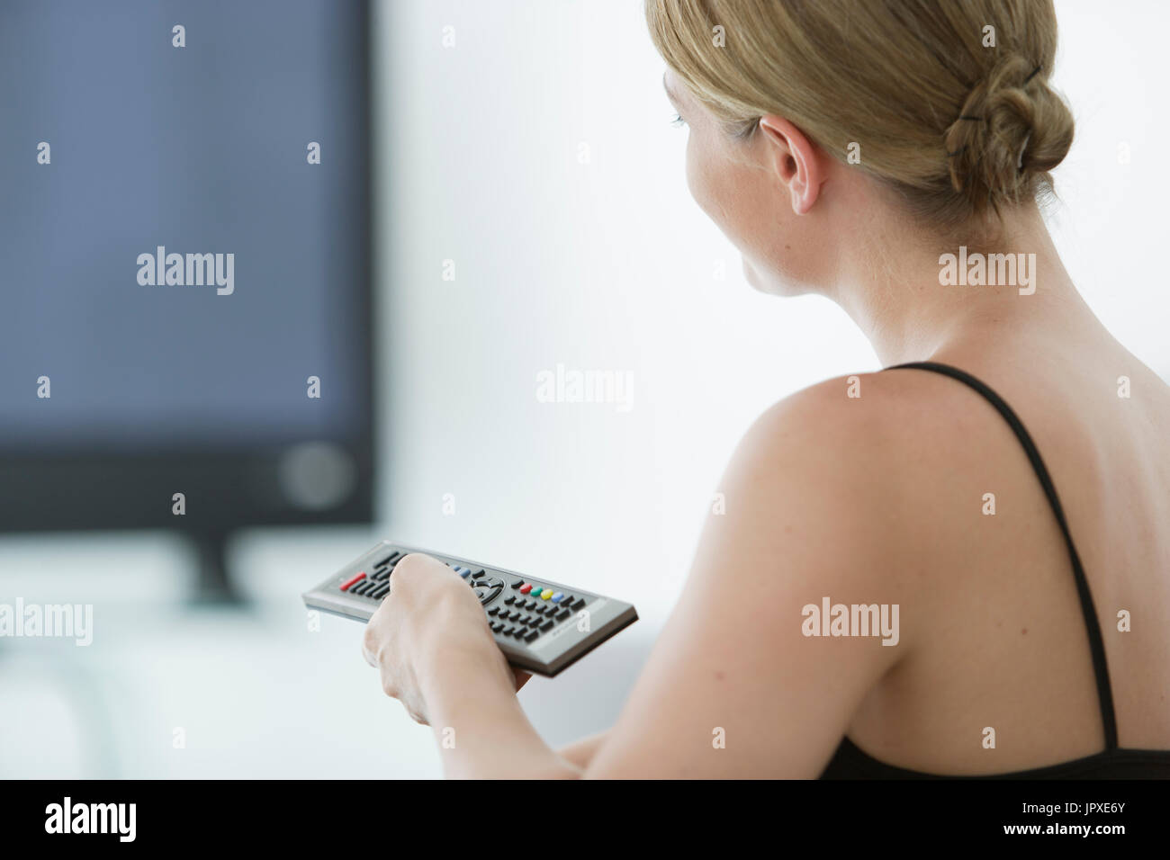 Young woman with remote devant plat Banque D'Images